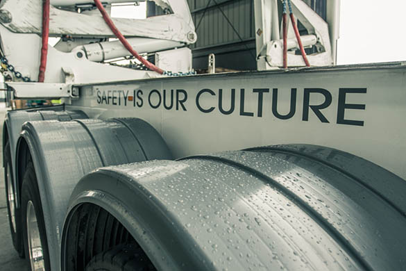 Close-up of truck wheels with water droplets and "SAFETY IS OUR CULTURE" slogan on the side.